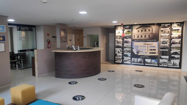 A hotel reception area with a curved counter, a seating area with chairs, and a wall displaying historical photos and information about the hotel.