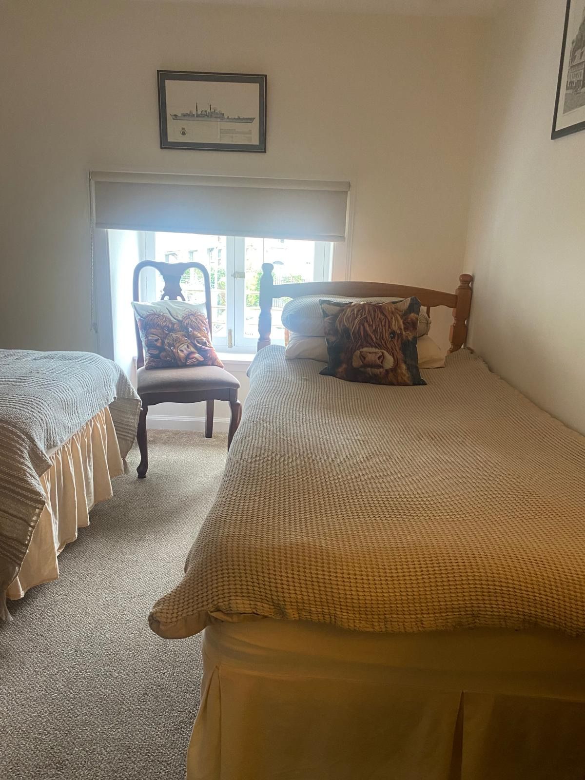 A bedroom with two single beds, a chair, and a window.