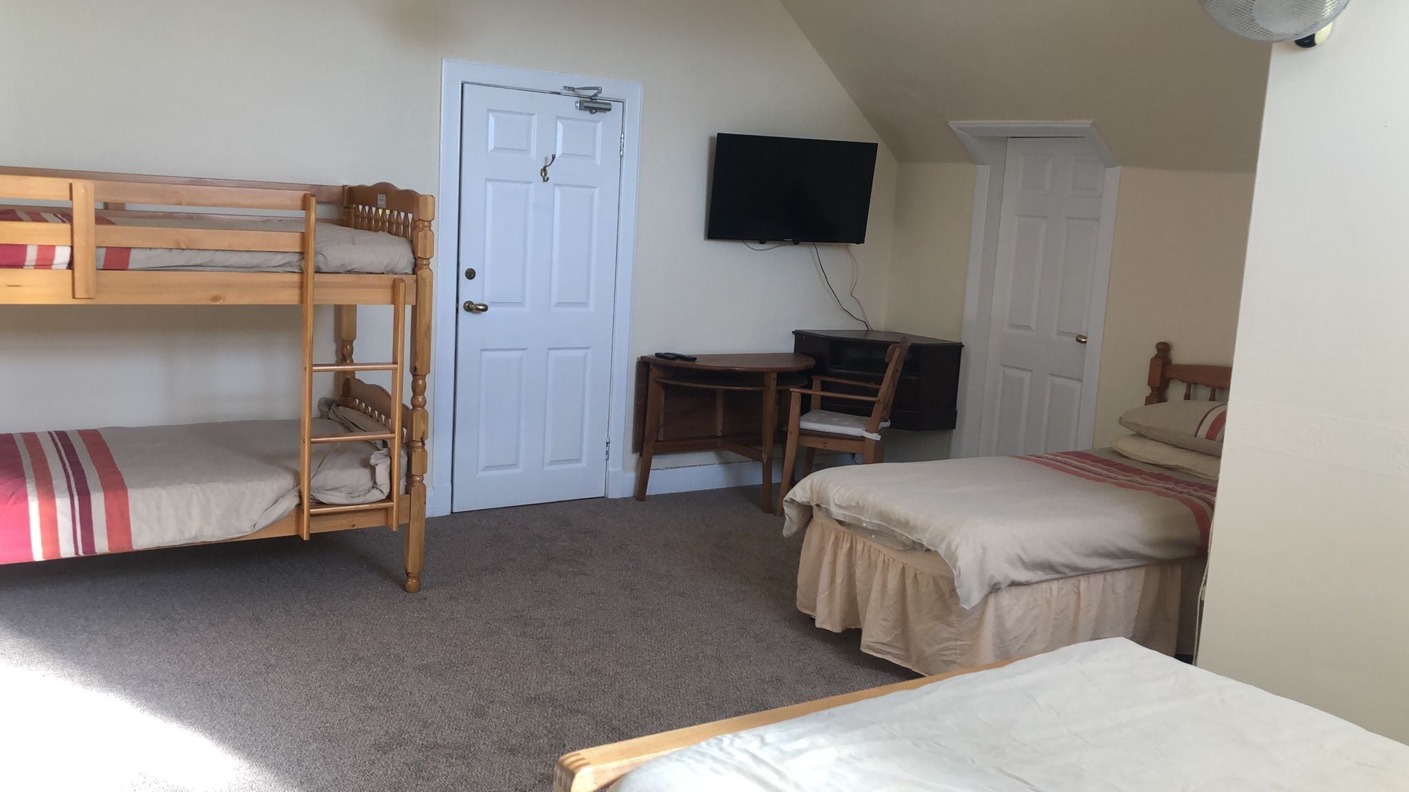 Un dormitorio con literas, un escritorio, una silla y un televisor.