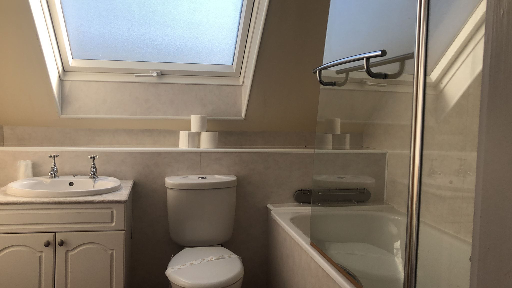 Et moderne badeværelse med ovenlys, badekar, toilet og håndvask.