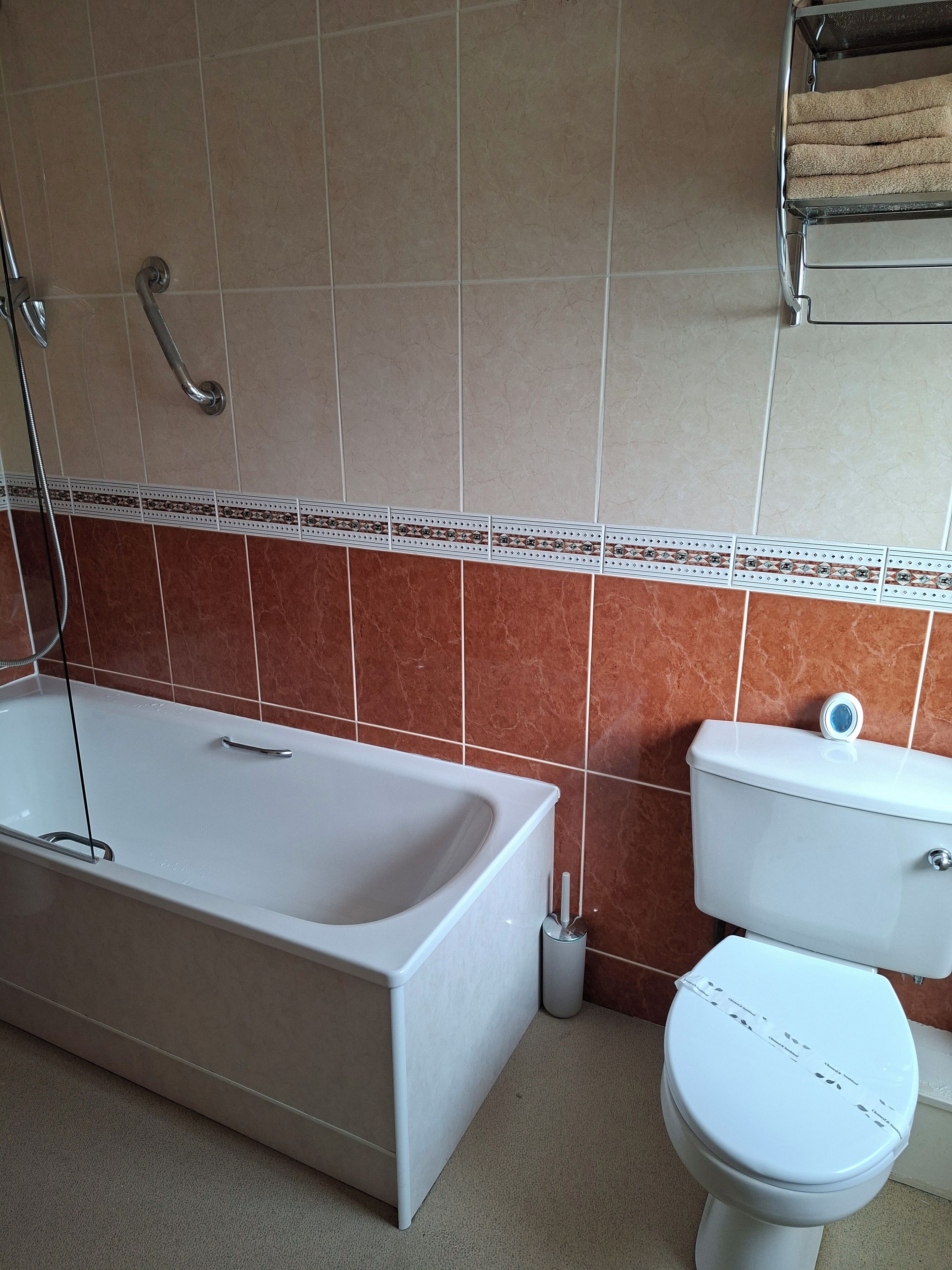 A bathroom with a bathtub, toilet, and a towel rack.