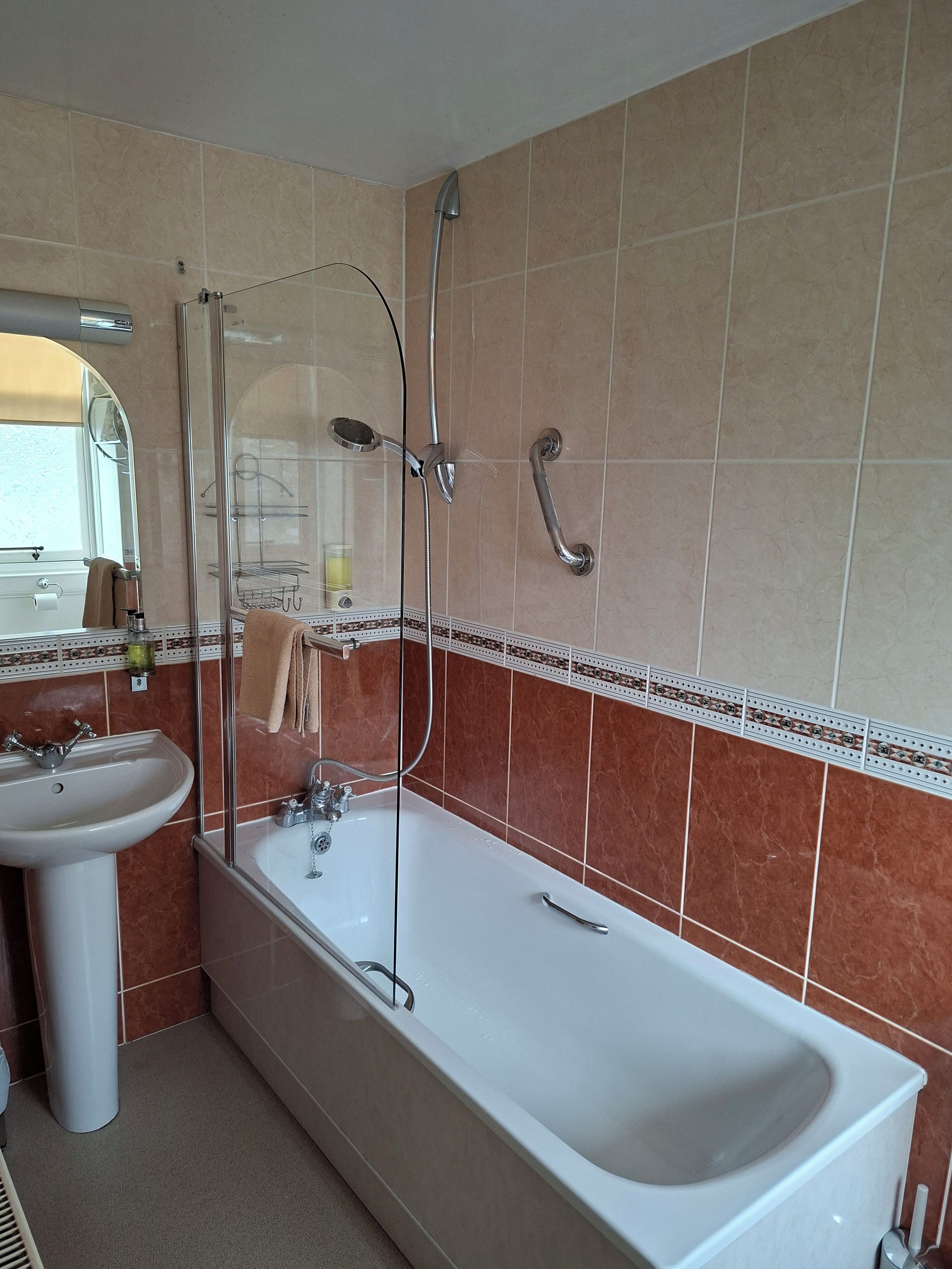 A bathroom with a bathtub, a sink, a shower enclosure, and a mirror.