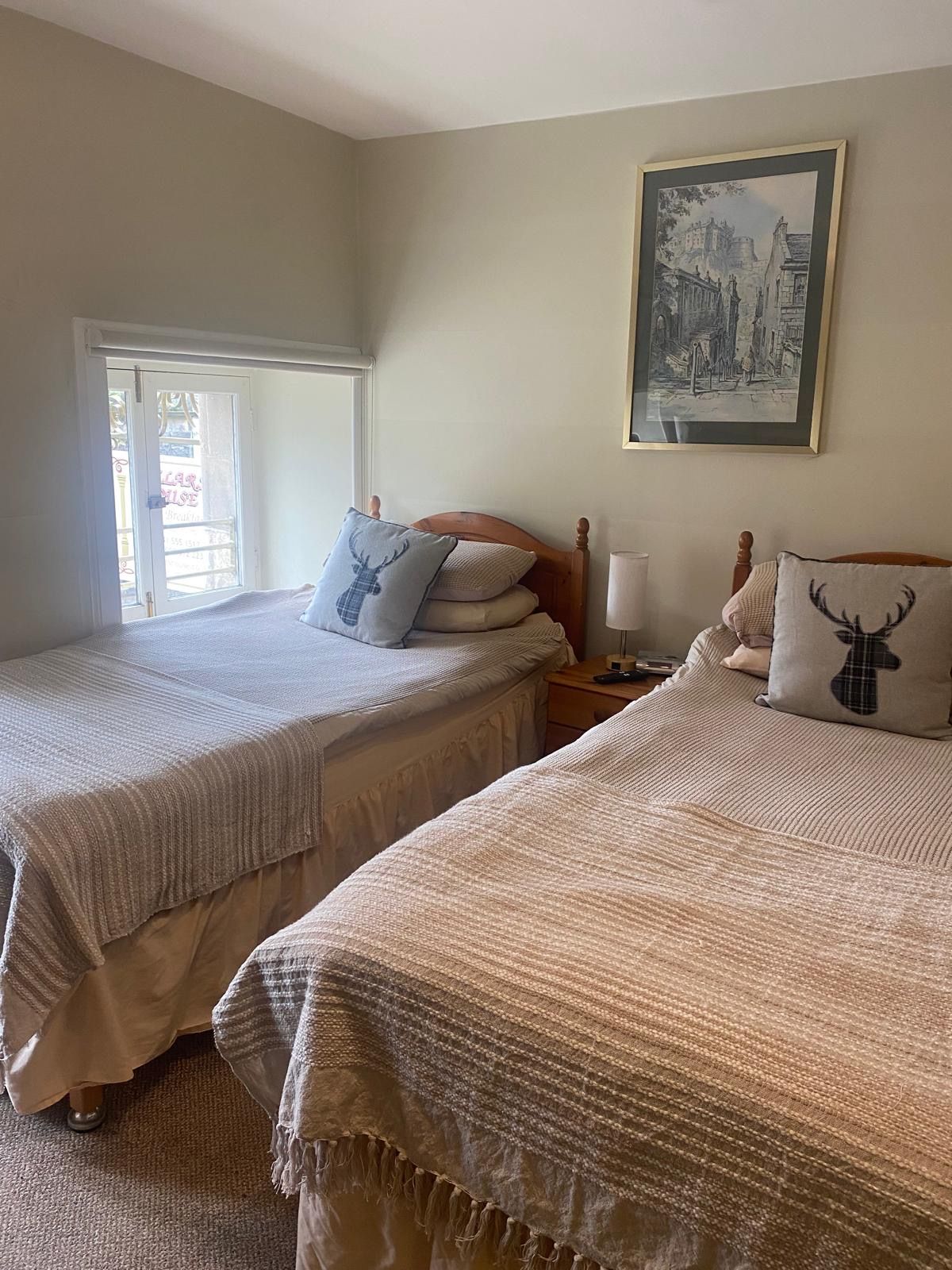 A bedroom with two beds, a nightstand, a lamp, and a framed picture on the wall.