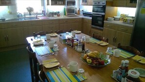 A kitchen with wooden cabinets, a dining table set for four, and various kitchen appliances.