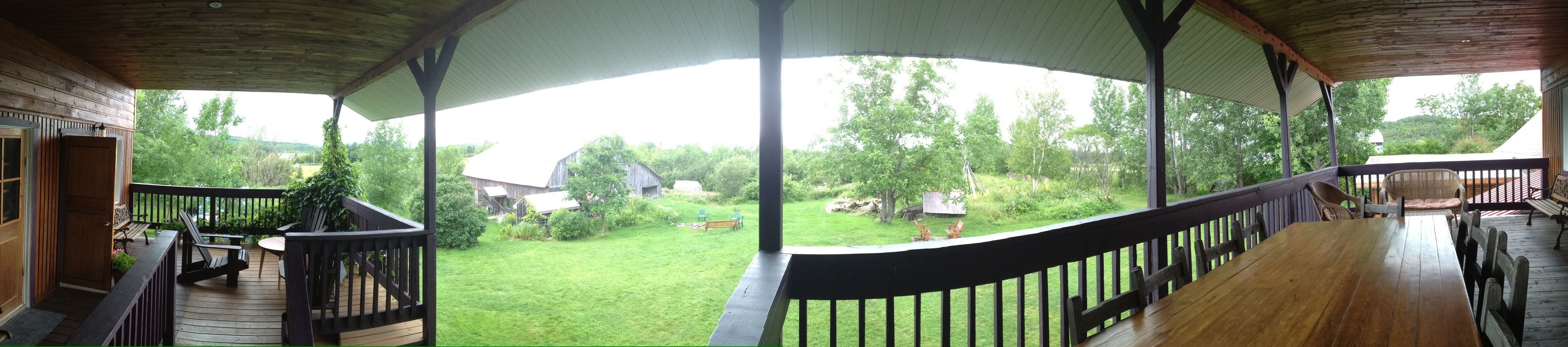 A covered outdoor area with a wooden deck, a dining table, and chairs.