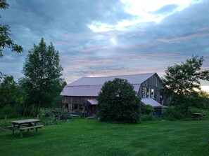 A rustic barn with a sloped roof, surrounded by lush greenery and trees. - L'Aubergine (Saint Hilarion)