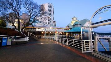 A waterfront promenade with a bridge leading to a restaurant and a sign for 'Warriorside Adventures'.