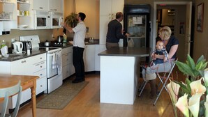 Eine moderne Küche mit weißen Schränken, einer zentralen Kochinsel und einem Essbereich mit Holztisch und Stühlen.