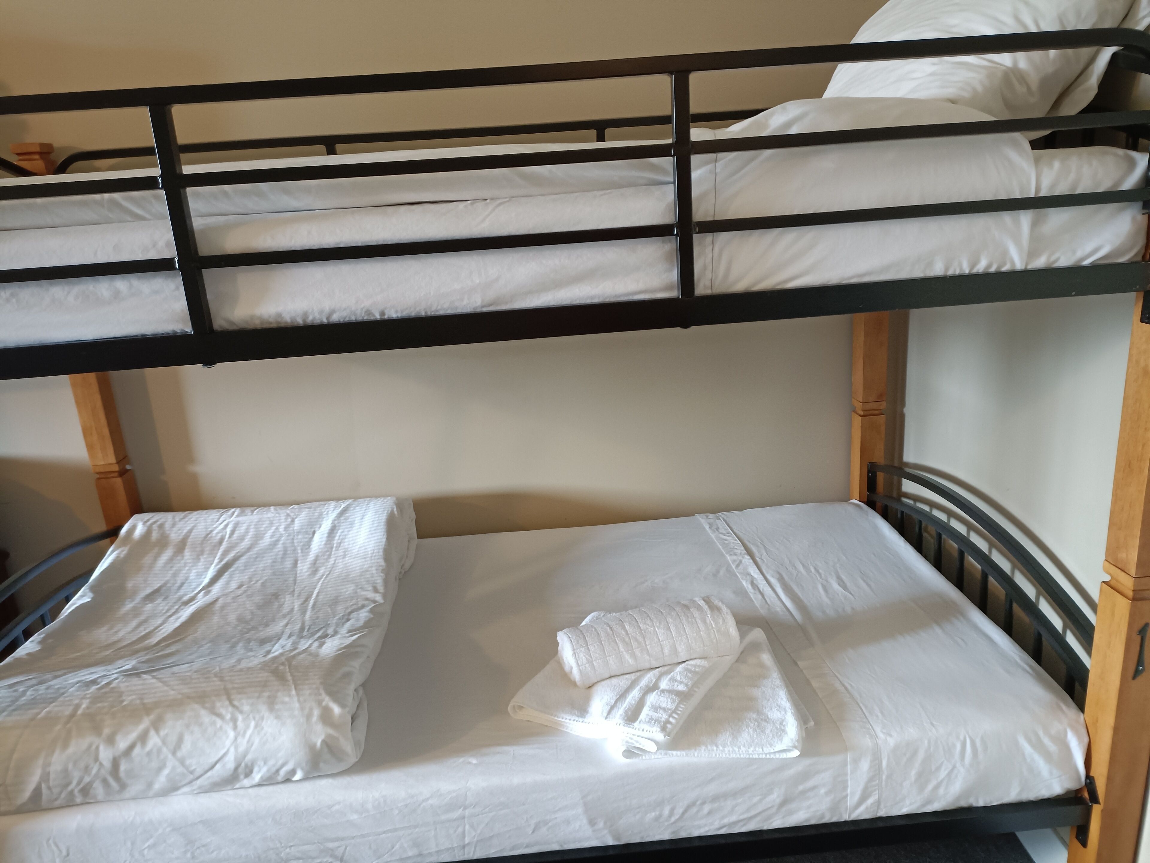 Un lit superposé avec une literie blanche et une serviette soigneusement pliée sur le lit du bas.