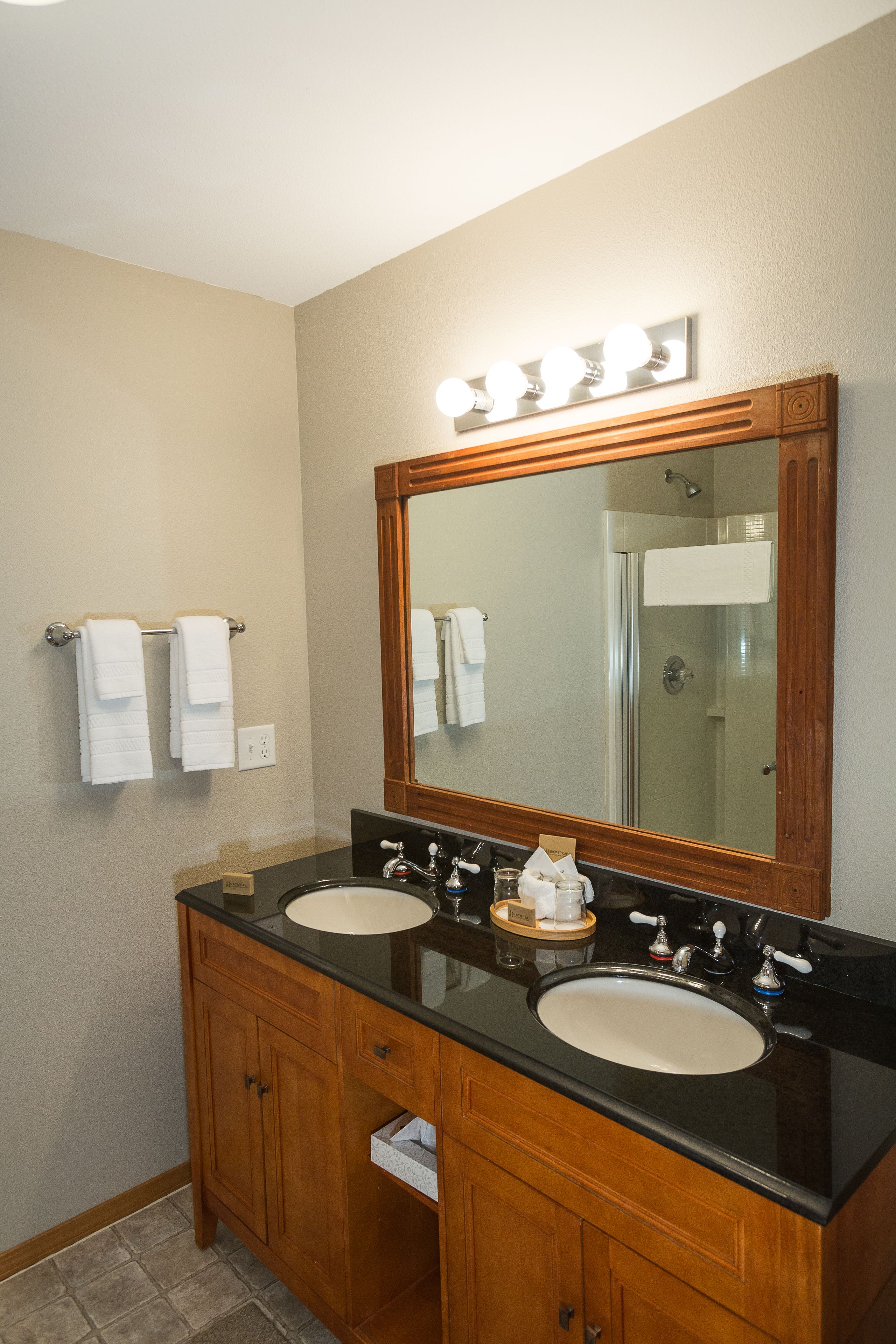 A bathroom with two sinks, a large mirror, and a towel rack.
