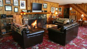 Una sala de estar acogedora con sofás de cuero, una chimenea, un televisor y cuadros en las paredes.