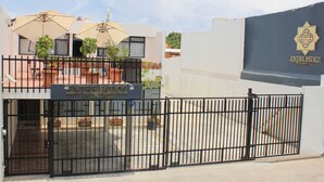 A gated entrance to a hotel with outdoor seating and a sign for 'Entre Patios Hotel Boutique'.