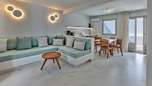 Ein modernes Wohnzimmer mit einer Eckcouch, einem Essbereich mit Holzsesseln und einer Küche im Hintergrund.