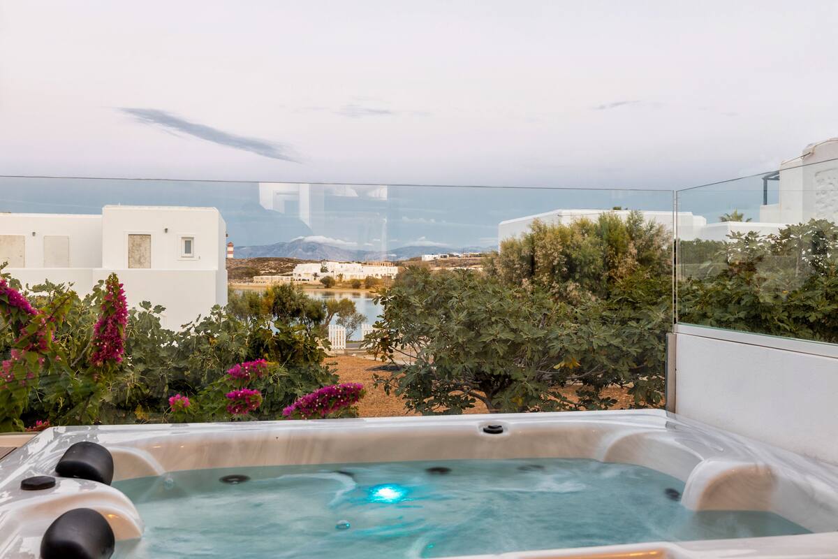 Un bain à remous offrant une vue dégagée sur un paysage montagneux, avec une étendue d’eau en arrière-plan.