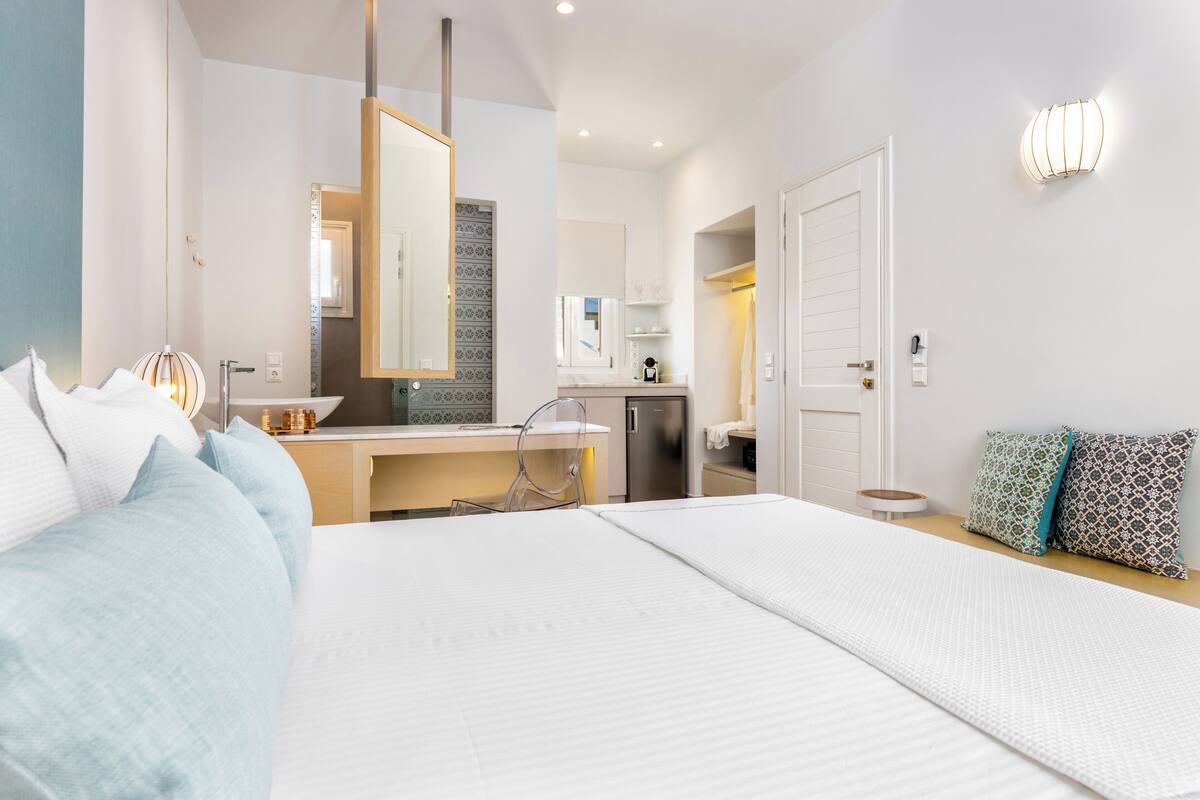 Une chambre d’hôtel moderne équipée d’un grand lit, d’un bureau et d’une kitchenette.