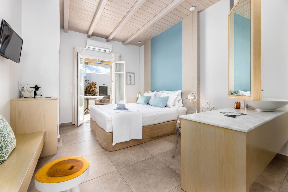 Une chambre moderne avec un lit, une table de chevet et une salle de bain équipée d’un lavabo et d’un miroir.