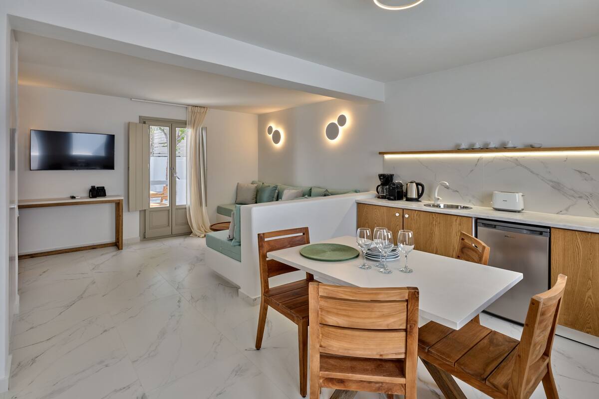 Une cuisine moderne avec un coin repas, un téléviseur fixé au mur et un canapé dans l’espace salon.