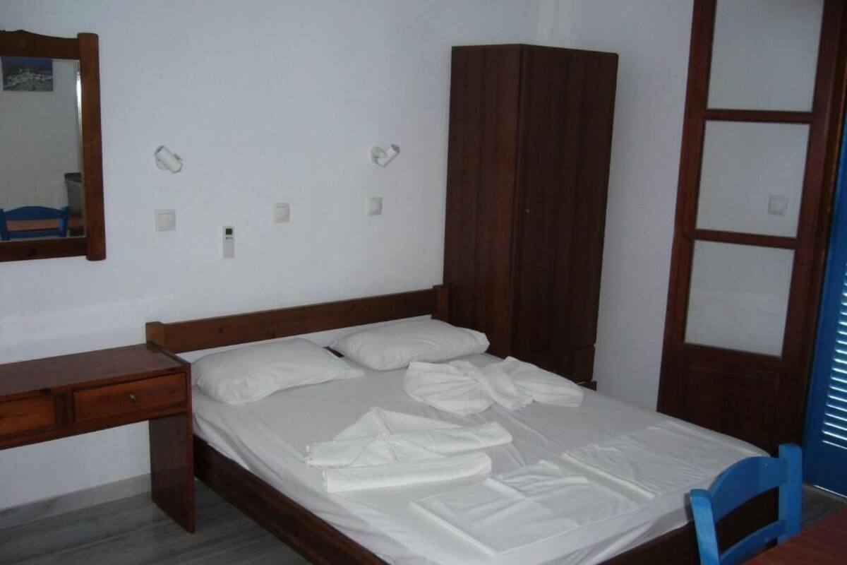 A bedroom with a wooden bed, a desk, and a wardrobe.