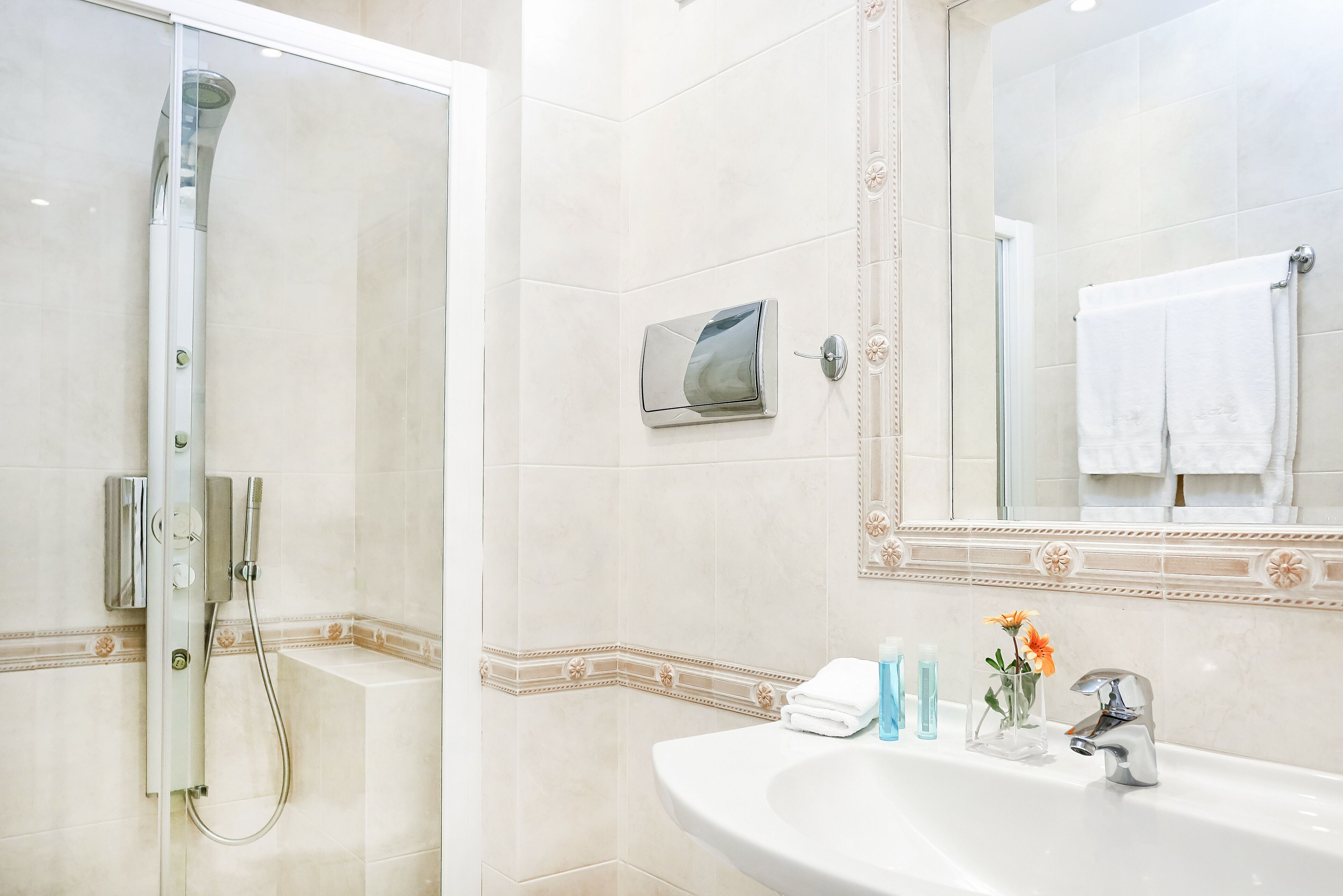 Un baño con ducha, lavamanos y espejo.