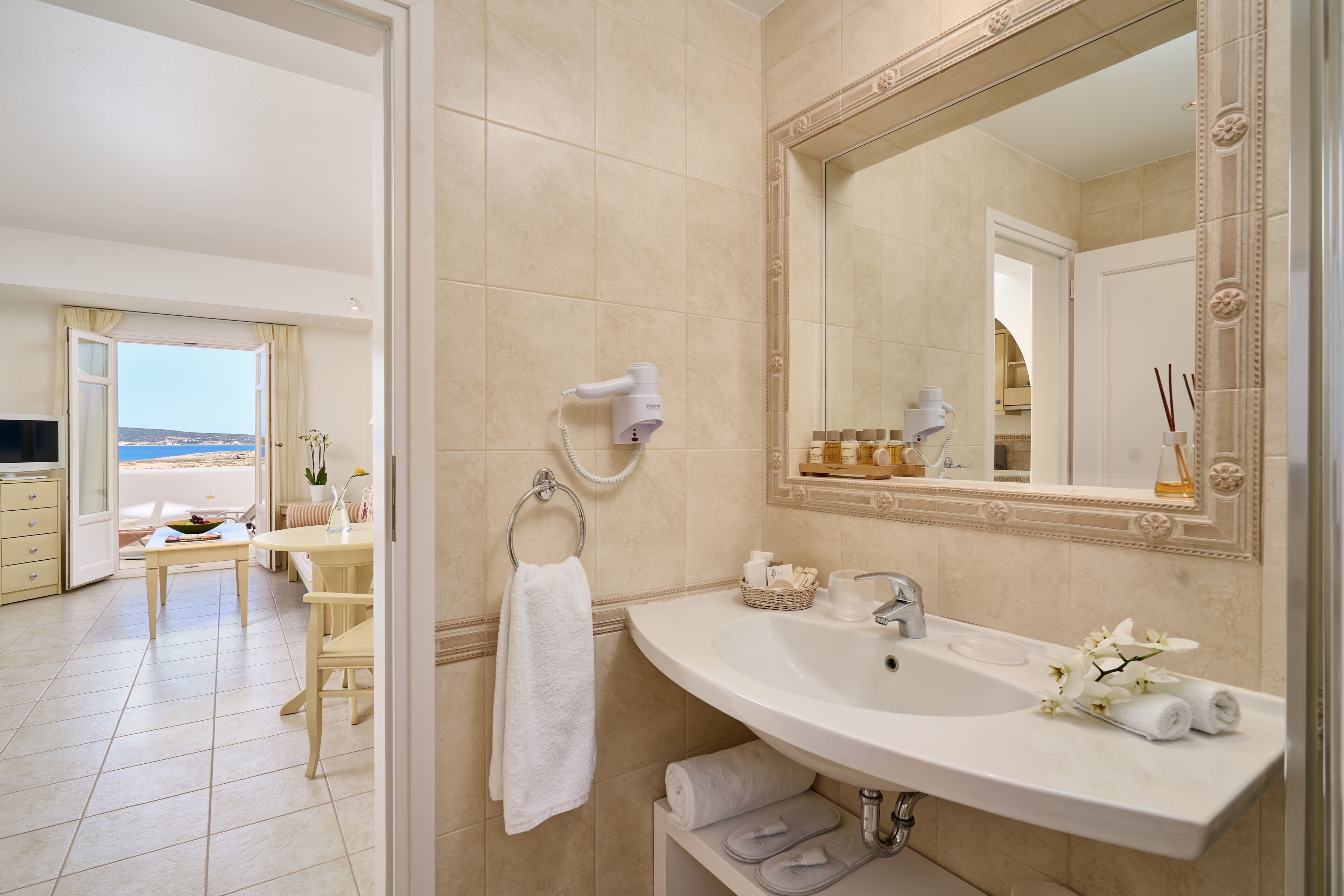 A bathroom with a large mirror, a sink, and a towel rack.