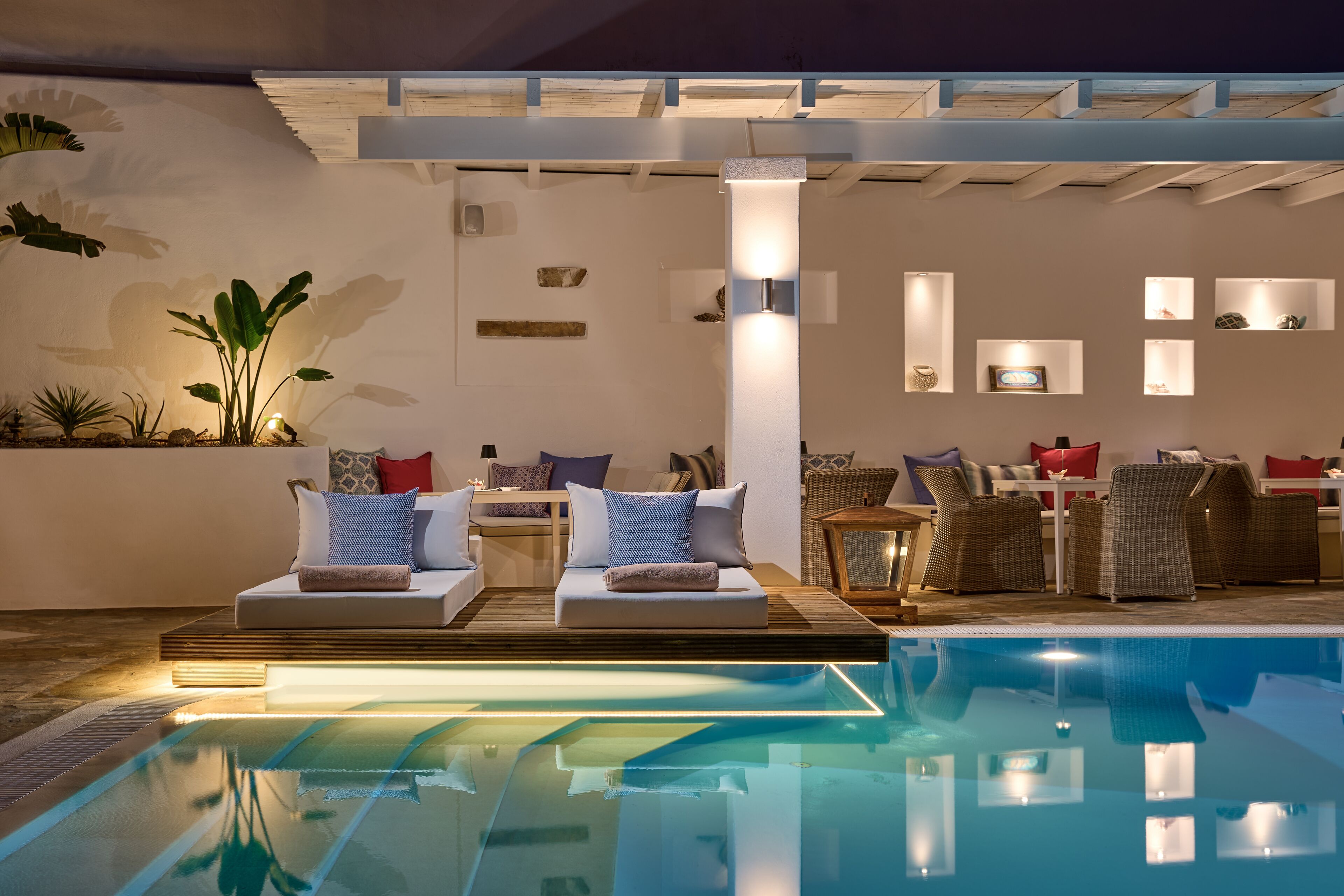 Un espace aménagé au bord de la piscine, comprenant un fauteuil de relaxation, une table à manger et la piscine elle-même.