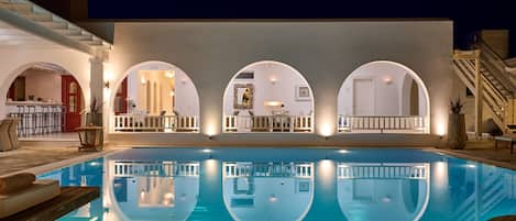 A swimming pool with a reflection of the adjacent building's interior.