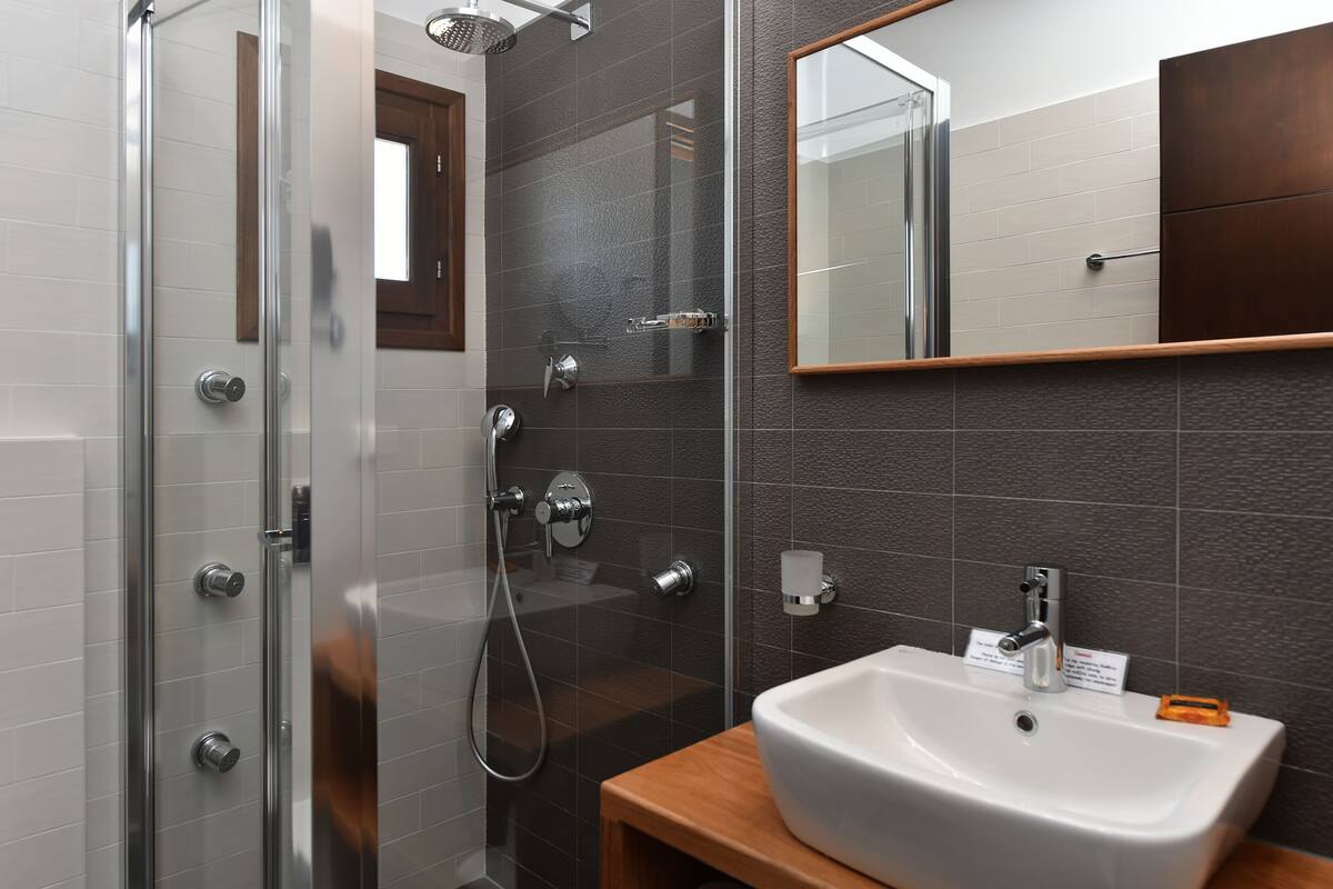 A modern bathroom with a glass-enclosed shower, a white sink, and a wooden vanity.