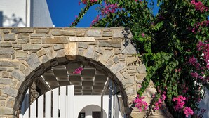 Un arco in pietra che conduce a un cancello bianco, con un cartello per 'Aella Residence' sulla destra.