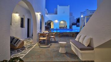 Un cortile con piscina, pavimento in pietra, pareti bianche e zone relax.