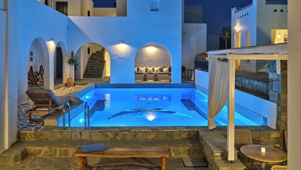 Area piscina con solarium in pietra, poltrone relax e una scala che conduce a una terrazza sul tetto.