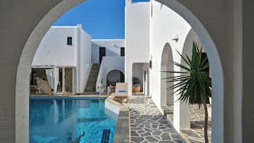 Relax by the serene pool surrounded by whitewashed buildings with arched doorways.