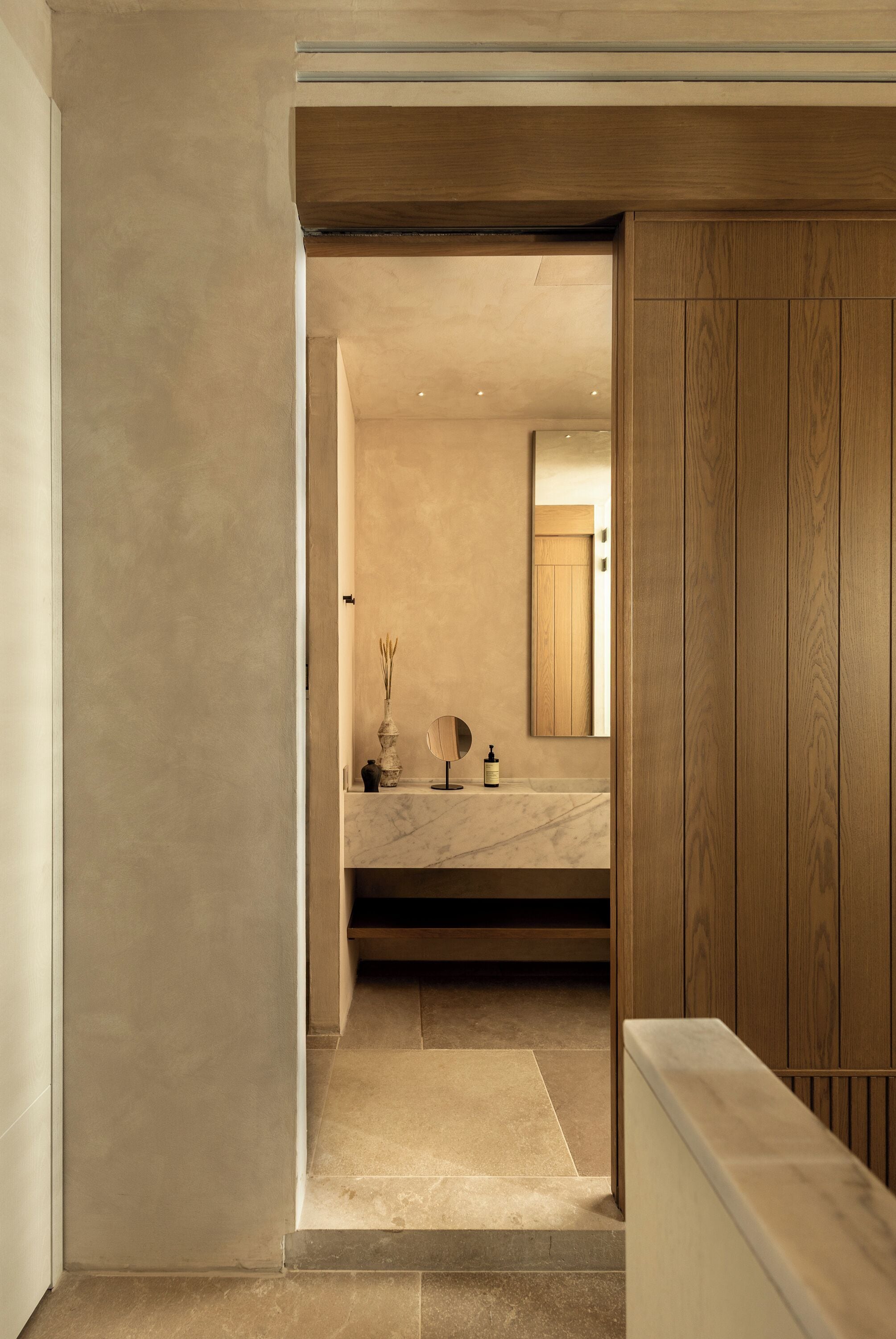 A modern bathroom with a marble sink, wooden paneling, and a mirror.