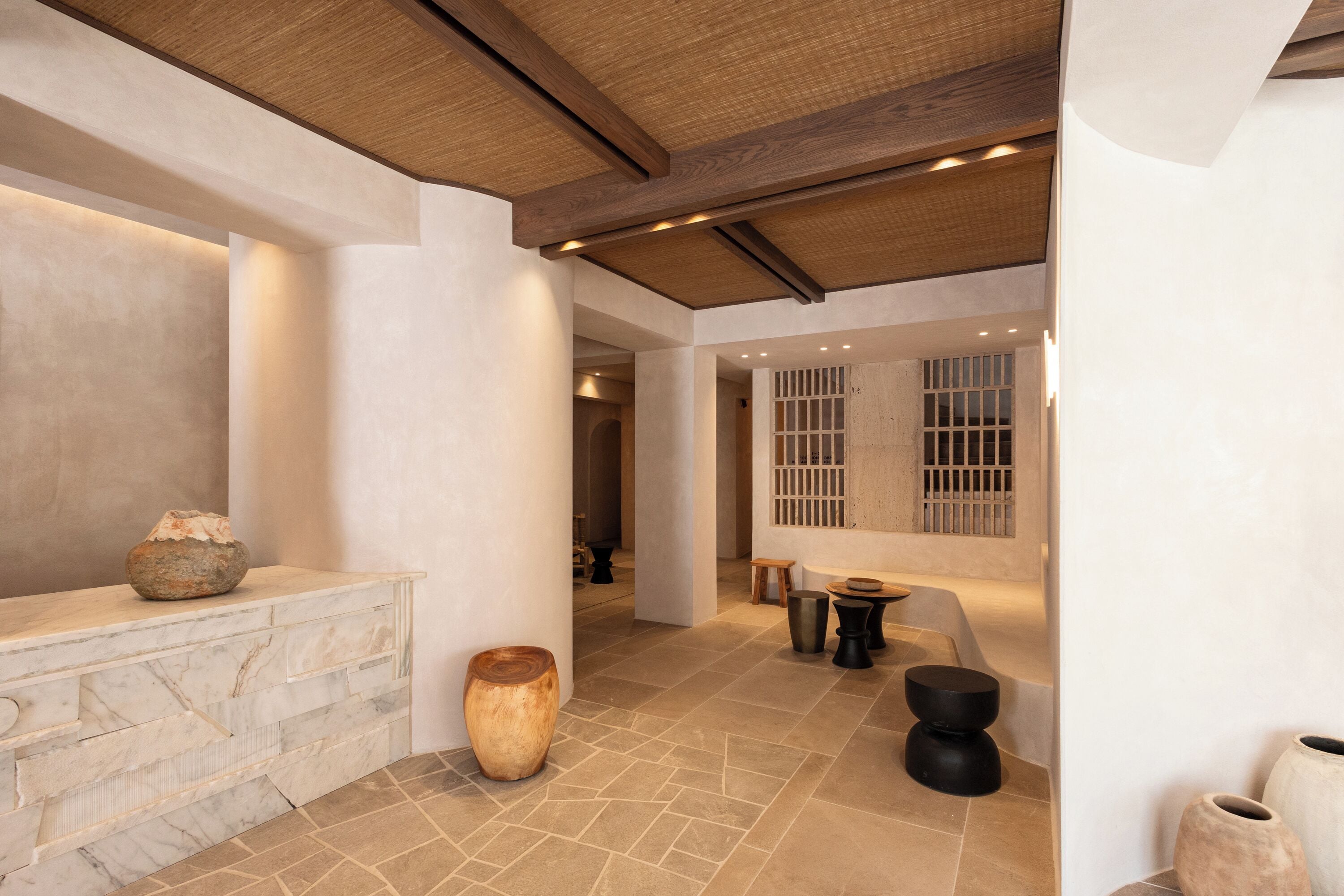 A spacious interior with a stone wall, a large vase, and a wooden bench.