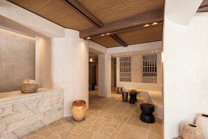 A spacious interior with a stone wall, a large vase, and a wooden bench.
