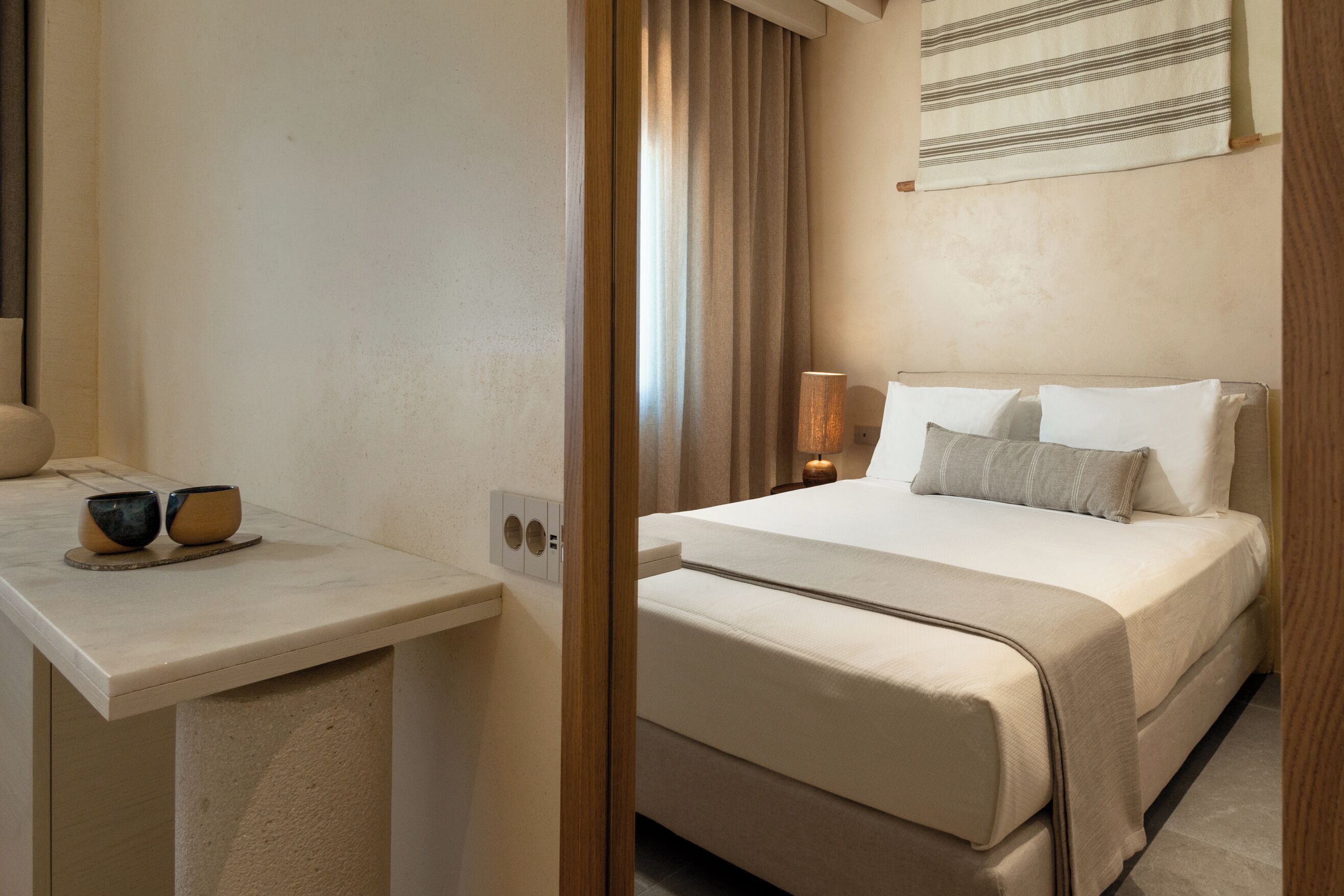 A hotel room with a bed, bedside table, and a mirror.