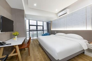 A modern hotel room with a large bed, a desk with a chair, a flat-screen TV, and a large window offering a city view. - Tixiang International Hotel (Suzhou)