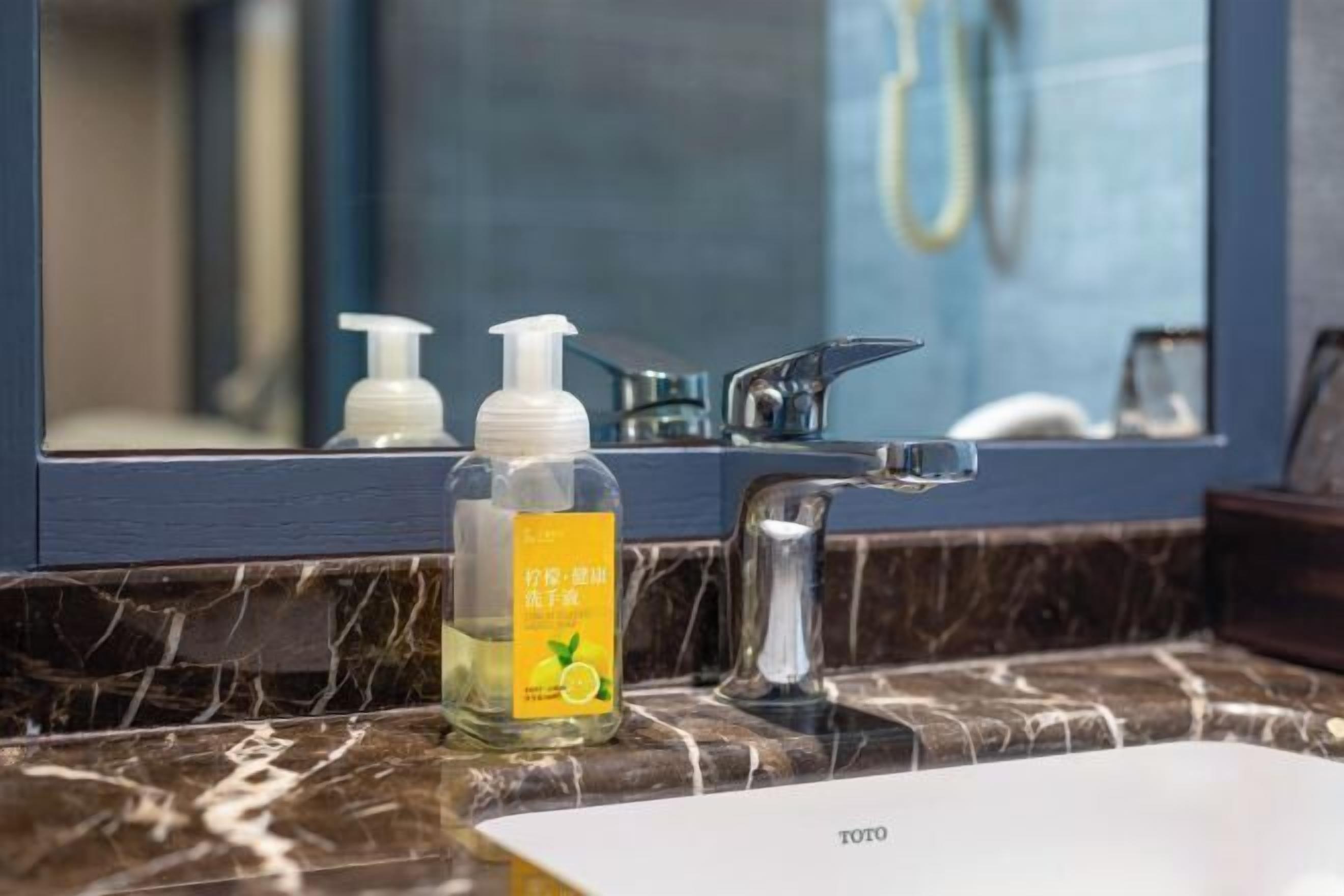 Une salle de bain avec un comptoir en marbre, un lavabo et deux distributeurs de savon pour les mains.