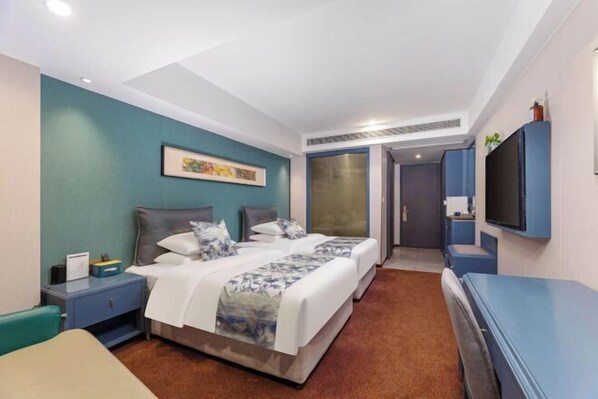 Habitación de hotel con dos camas, televisión, escritorio y armario.
