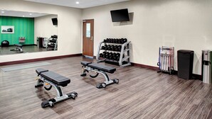 A gym with exercise equipment, a mirror, a television, and a door. - Holiday Inn Express & Suites Coldwater by IHG (Coldwater)