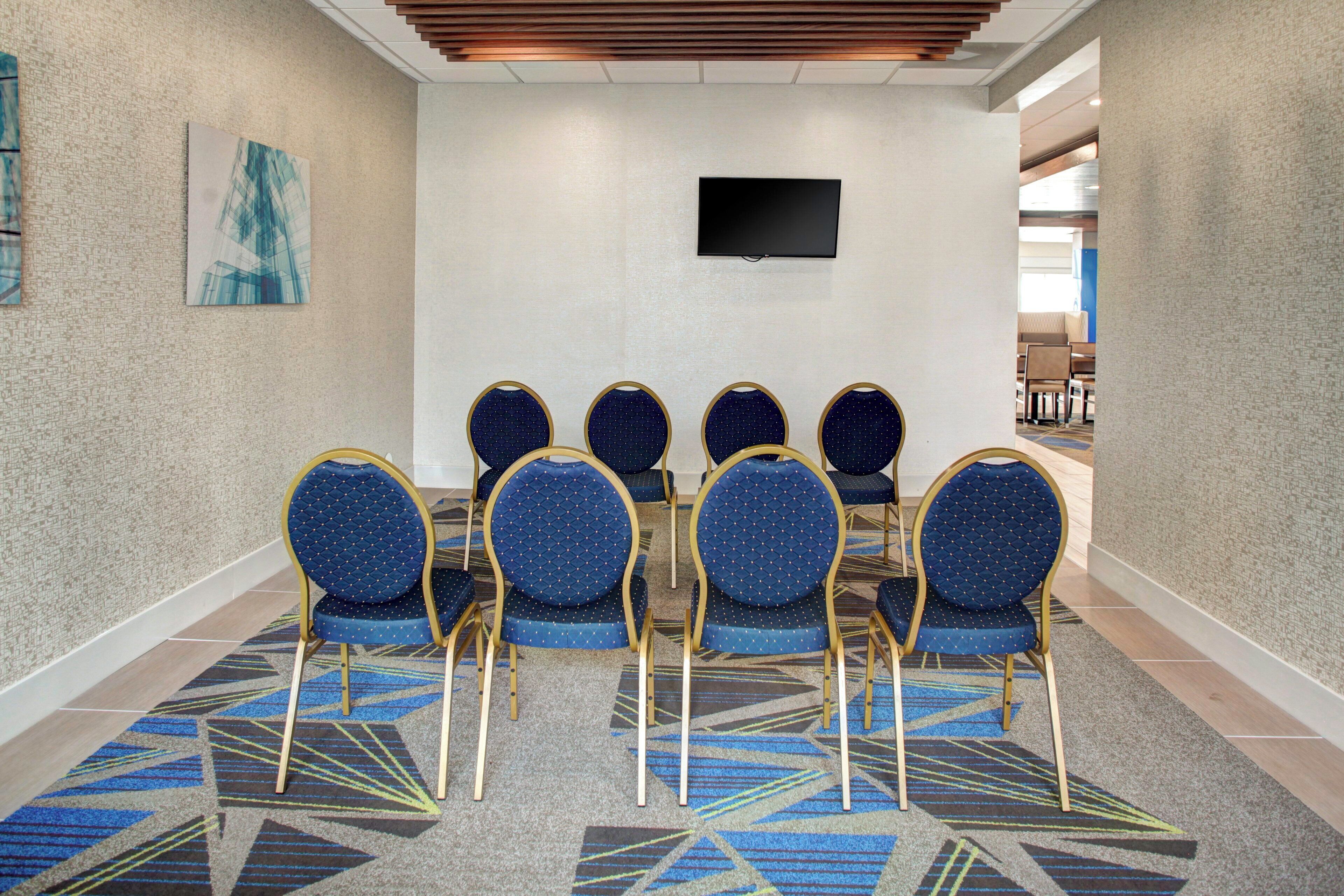 A conference room with six chairs and a flat-screen TV on the wall.