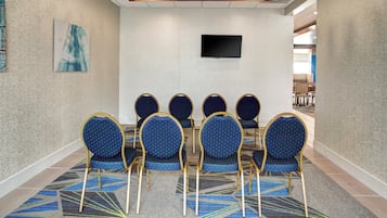 A conference room with six chairs and a flat-screen TV on the wall.