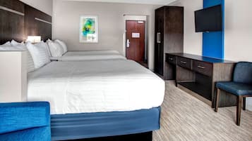 A hotel room with a large bed, a desk, a chair, a TV, and a door.