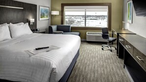A hotel room with a large bed, a desk, a chair, a window with a view, and a TV. - Holiday Inn Express & Suites Coldwater by IHG (Coldwater)