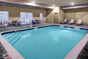An indoor swimming pool with a 3ft depth, surrounded by lounge chairs and a sunbed.