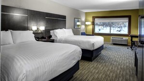 A hotel room with two beds, a large window with a view of a snowy landscape, a desk with a lamp, and a wall-mounted air conditioner. - Holiday Inn Express & Suites Coldwater by IHG (Coldwater)