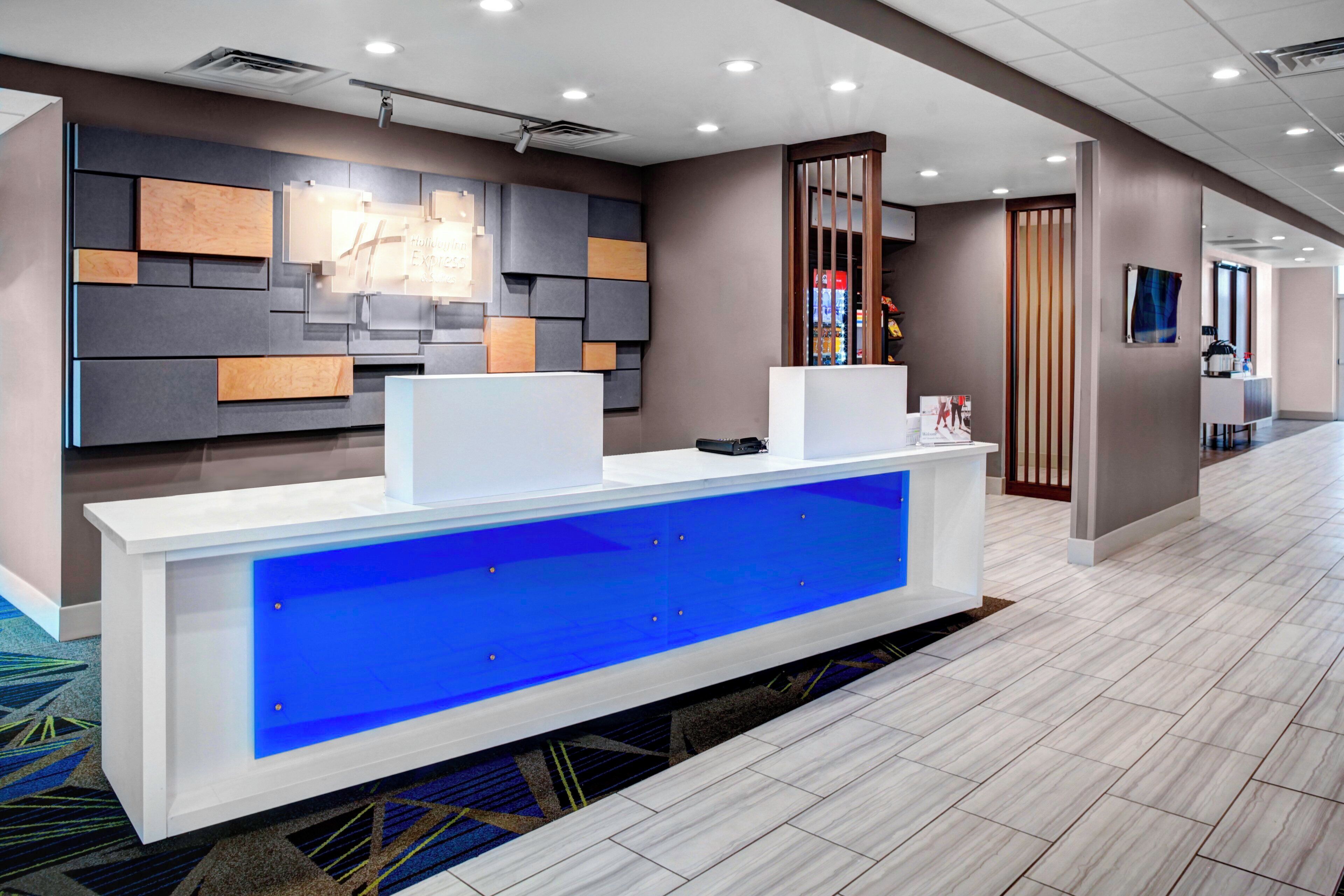 A reception desk with a blue illuminated panel, a modern wall design, and a carpeted floor.
