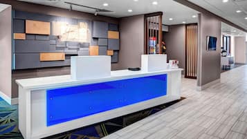 Una recepción con un panel iluminado en azul, un diseño moderno en la pared y piso alfombrado.