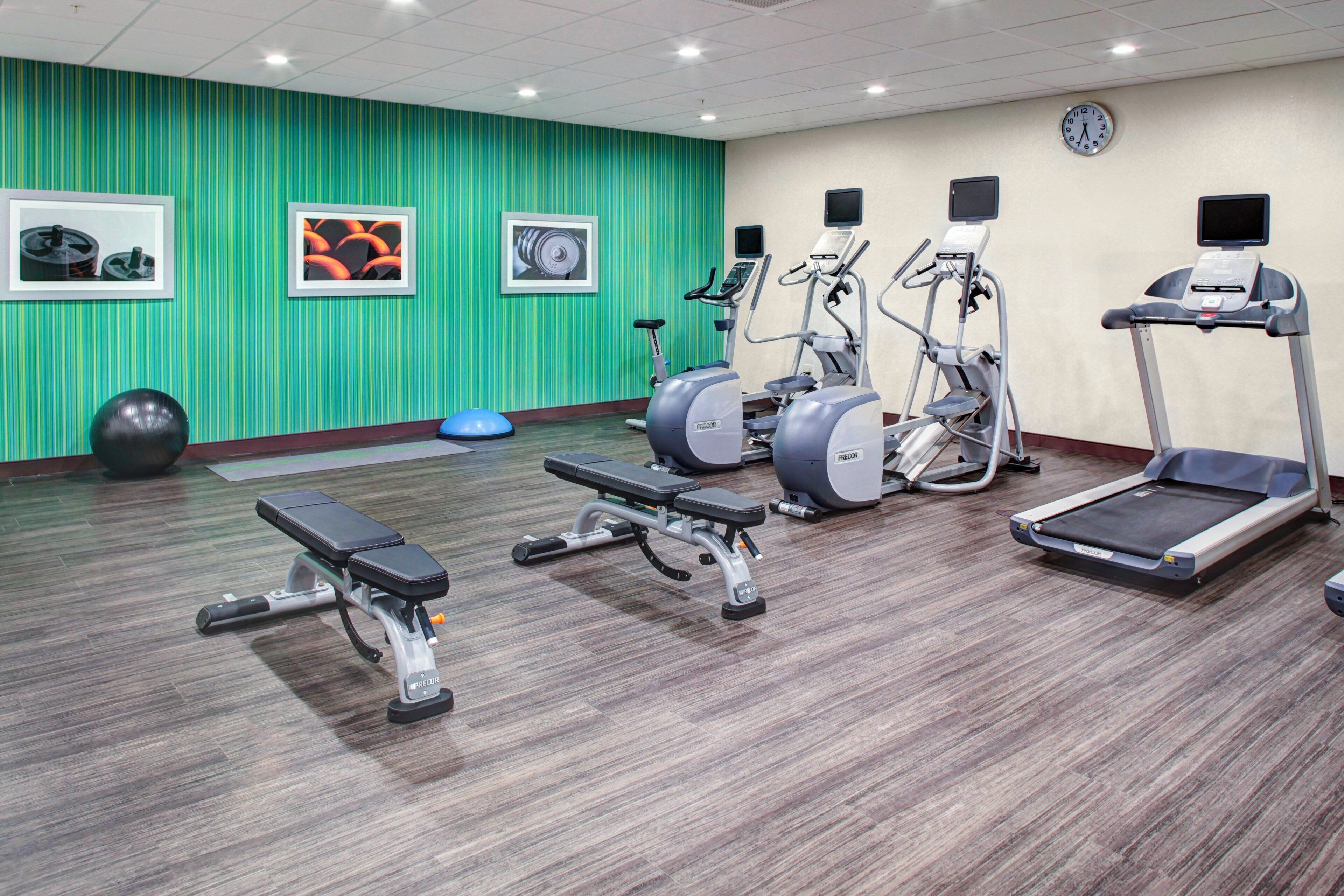 Ein Fitnessraum mit Laufbändern, Crosstrainern und einer Bank.