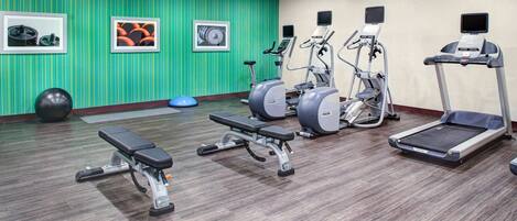 A gym with treadmills, elliptical machines, and a bench.