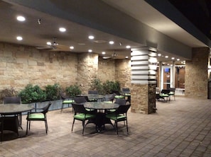An outdoor patio area with stone walls, multiple tables and chairs, and ceiling lights. - Holiday Inn Trophy Club by IHG (Roanoke)
